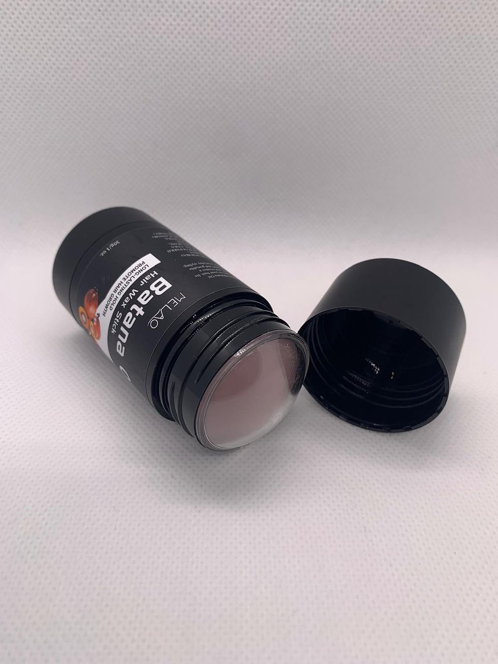 Stick noir Batana Plus, ouvert avec son capuchon posé à côté.