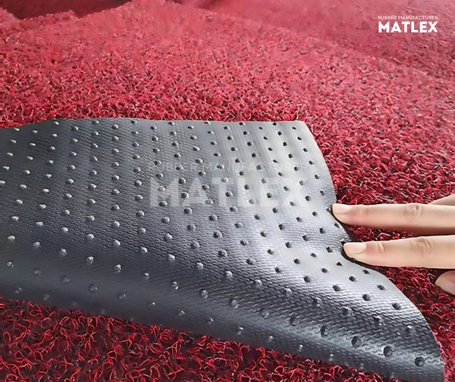 Close-up of the non-slip backing of the black and red spaghetti coil matting, highlighting the textured underside that prevents slipping.