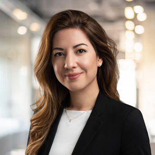 Female executive with long hair and warm smile – natural light portrait in modern office environment.