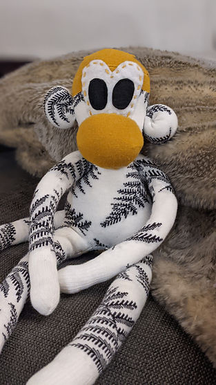 Mono peluche hecho de dos calcetines de blanco y negro con accentos en el color dorado
