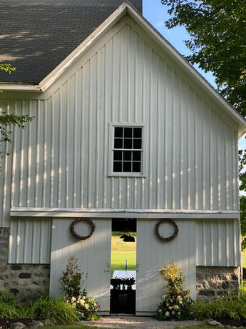 Sunlight falling across a white barn door and wedding flowers