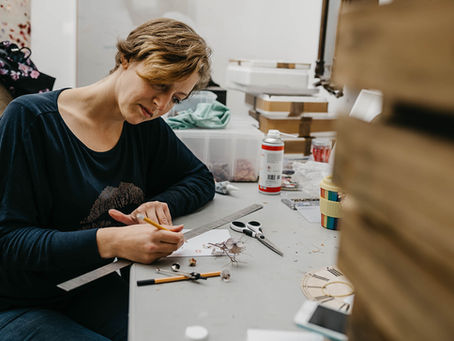 Artist, Anna Masters, sketches out new ideas at a messy desk
