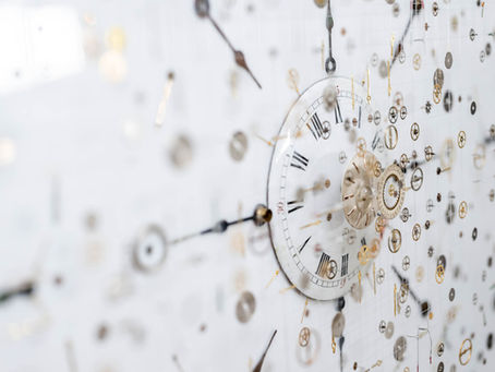 Close up image of a three-dimensional clock artwork, with watch parts suspended on nylon