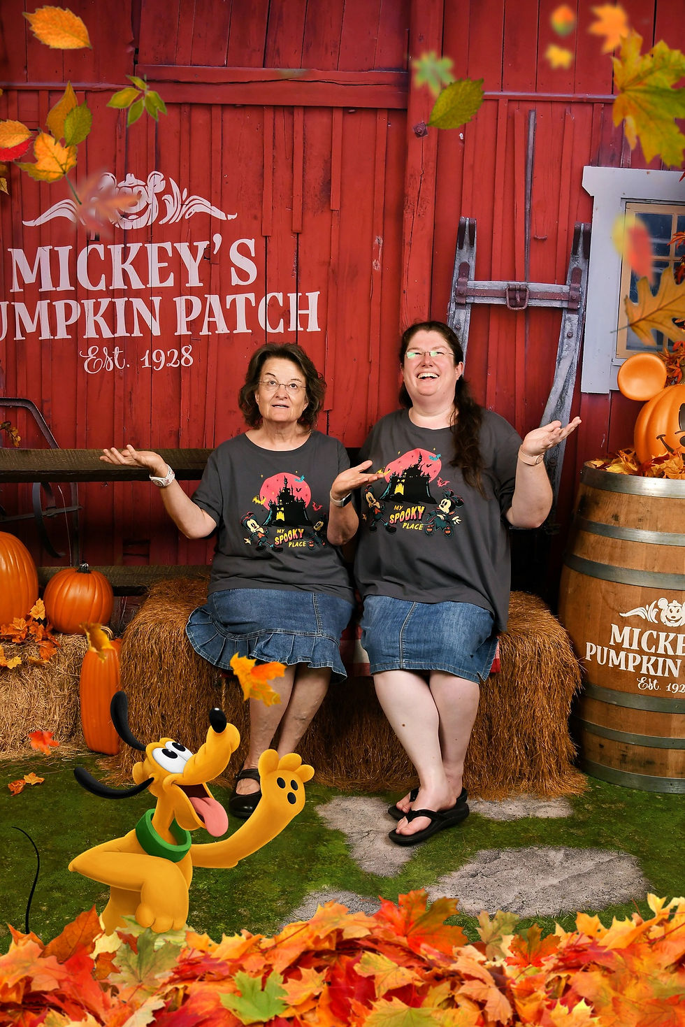 Two women are sitting on hay bales in front of a red barn backdrop that reads “Mickey’s Pumpkin Patch Est. 1928.” Both are wearing matching gray “My Spooky Place” Halloween shirts and denim skirts. They are smiling and holding their hands up as colorful autumn leaves fall around them. Pumpkins and hay bales decorate the scene, along with a wooden barrel topped with a Mickey-shaped pumpkin. A playful Pluto character is digitally added at the bottom, joyfully reaching for the falling leaves.