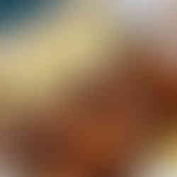 A tray of golden-brown sweet garam masala donuts drizzled with glaze sits beside a large syringe filled with creamy sauce, ready for filling or dipping. The donuts look warm, fluffy, and dusted with sugar, creating a playful and indulgent presentation.