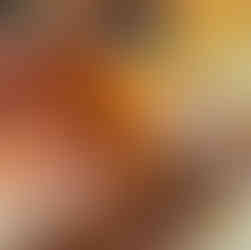 A hand holds a sweet garam masala donut while filling it with creamy sauce from a large syringe. More golden-brown donuts sit in a tray below. This is a close up view of the Sweet Garam Masala Donut from eet