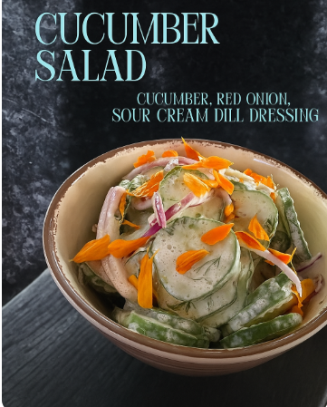 A bowl of cucumber salad garnished with orange flower petals. The salad contains sliced cucumbers, red onion, and is coated in a sour cream dill dressing. The background is a dark textured surface, and the text on the image reads "Cucumber Salad - Cucumber, Red Onion, Sour Cream Dill Dressing." This is the Cucumber Salad at the Polite Pig in Disney Springs.