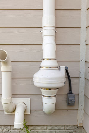 PVC pipes attached to the electrical motor of a residential radon mitigation system TIt su