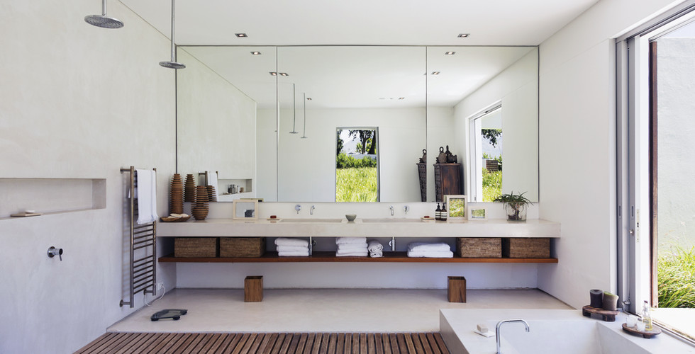 Luxury Modern Master Bathroom Remodeling Construction Project in Coral Gables, Florida with floating double undermount sinks and double faucets, full back wall mirror, combination of wood strip and matt crema marfil floor tiles and ground built-in bath tub.