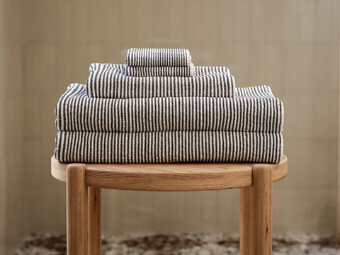 3D render of folded towels on wooden stool in bathroom setting