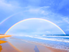 blue skies, rainbow over the sea and golden sand