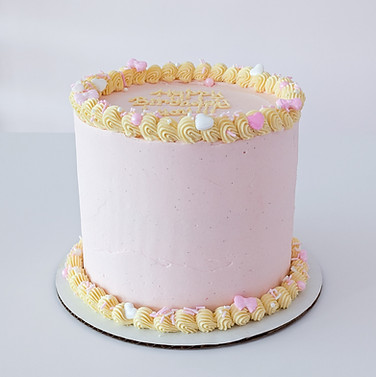 Photo of a pink cake with yellow classic border piping around the top and bottom