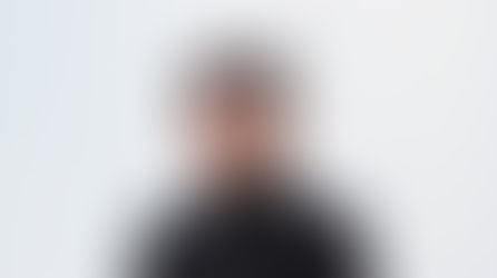 Portrait of TMD’s creative director in a black coat, calm expression, white ribbed façade — ArchViz