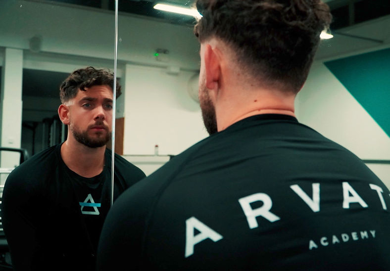 Focused coach looking in the mirror during a gym session, reflecting dedication and mindset
