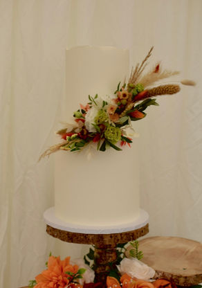 Two tiered white wedding cake with autumn coloured flowers