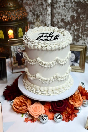 Single tiered wedding cake in popular white vintage piping design with "till death" themed topper and burnt orange coloured flowers