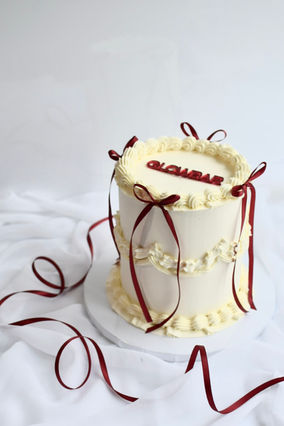 White cake decorated with vintage piping and red bows