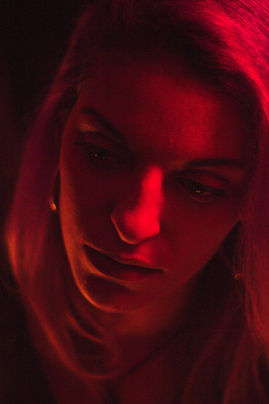 Retrato de uma mulher sobre fundo preto e iluminada apenas com uma luz vermelha.