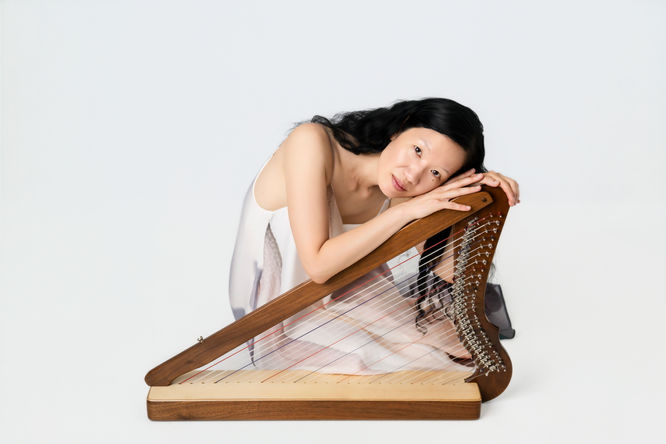 Woman with harp on white backdrop in studio