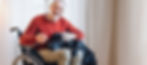 Man in wheelchair petting a dog at home
