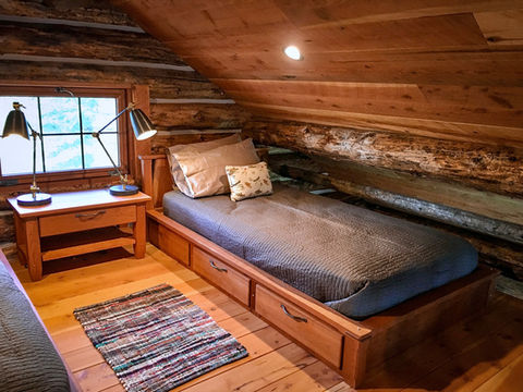 Hand built cherry storage bed in a small log cabin loft