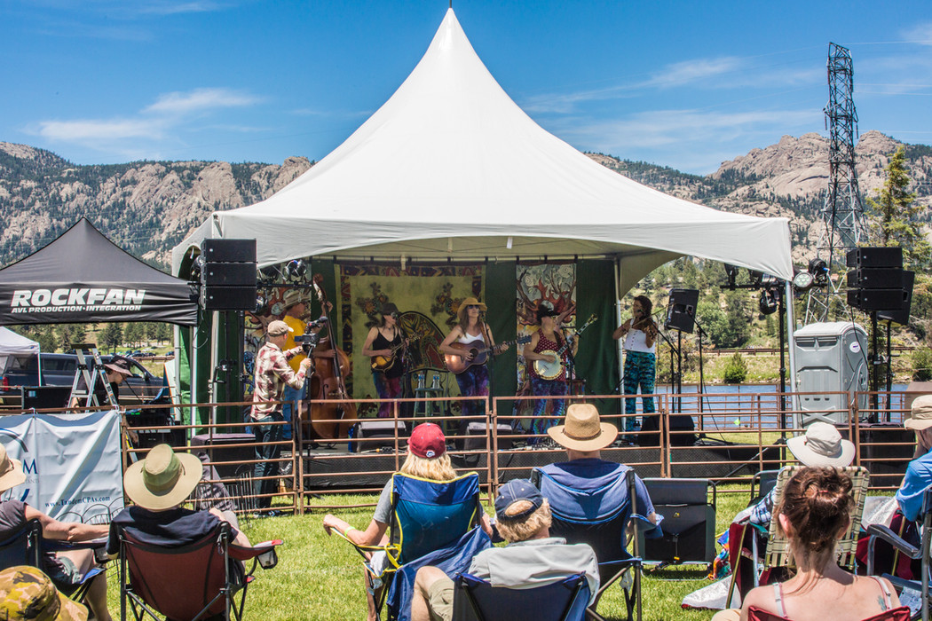 band on stage under tent in mountains