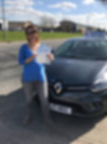 Smiling woman wearing glasses in front or learner vehicle