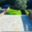 Garden with paved patio and grass area with tree
