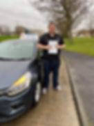 Smiling man beside learner car with pass certificate