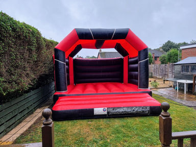 Large red and black bouncy castle in garden