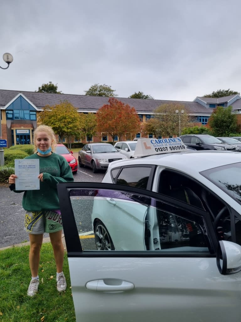 Female student stood behind open car door with certificate