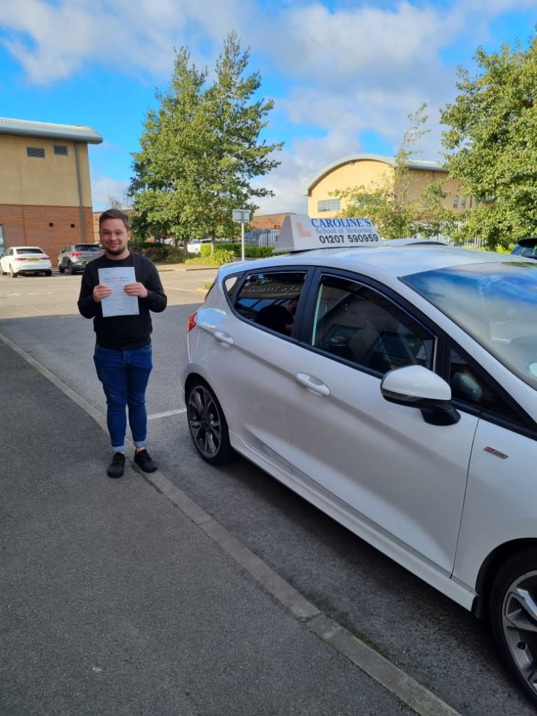 Student holding pass certificate next to white car