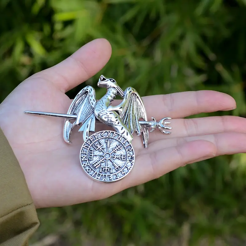 Thumbnail: Silver dragon brooch with a circular shield in palm.