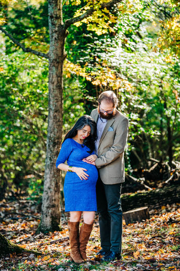 Expecting parents standing in golden afternoon light, cradling her baby bump in Nashville, TN.