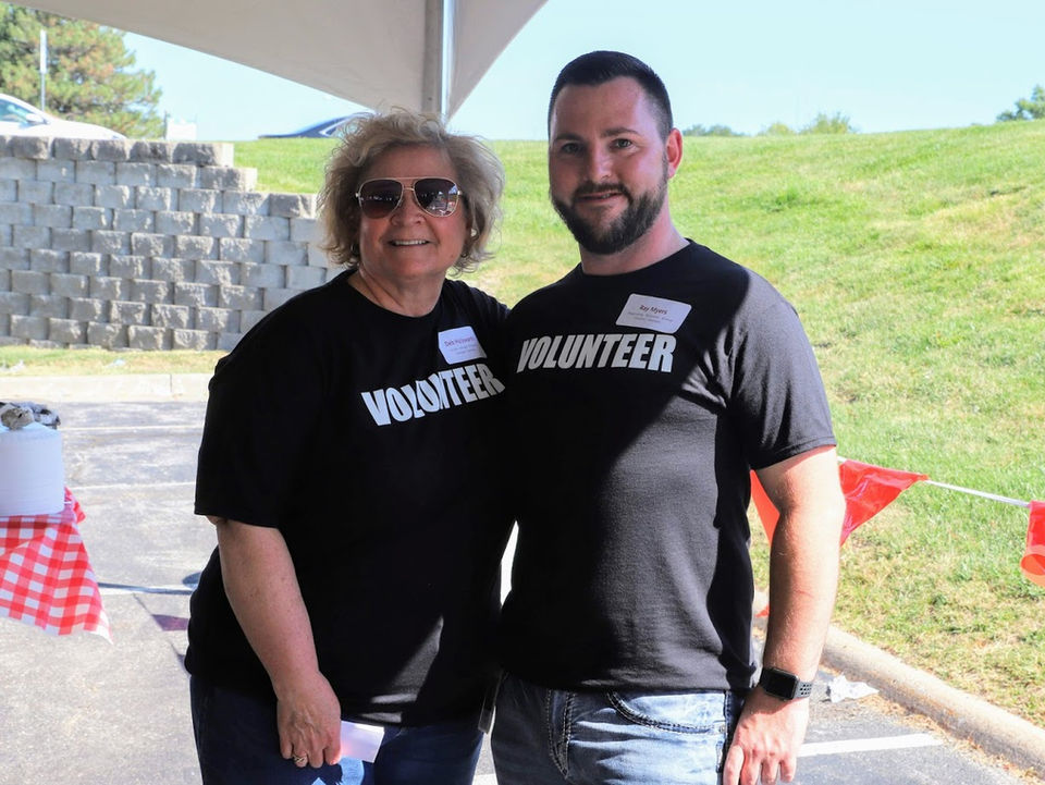 Two Signature Performance volunteers smiling at an outdoor community event