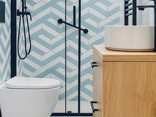 Modern bathroom with black-framed shower, wall-hung toilet, wood vanity and blue chevron tiles beside a washer.