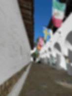 An alley lined with white buildings and flags hanging in Santa Barbara.