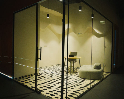 A modern glass-walled meeting room with a unique circular black and white patterned rug, a portfolio piece of high-end commercial interiors.
