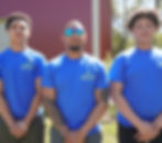 The owner and two collision repair team members standing in front of a red auto body shop