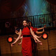 Young performer in a red costume standing on stage during a children’s theatre performance.