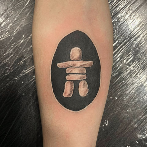 Black Inukshuk tattoo on the upper arm.