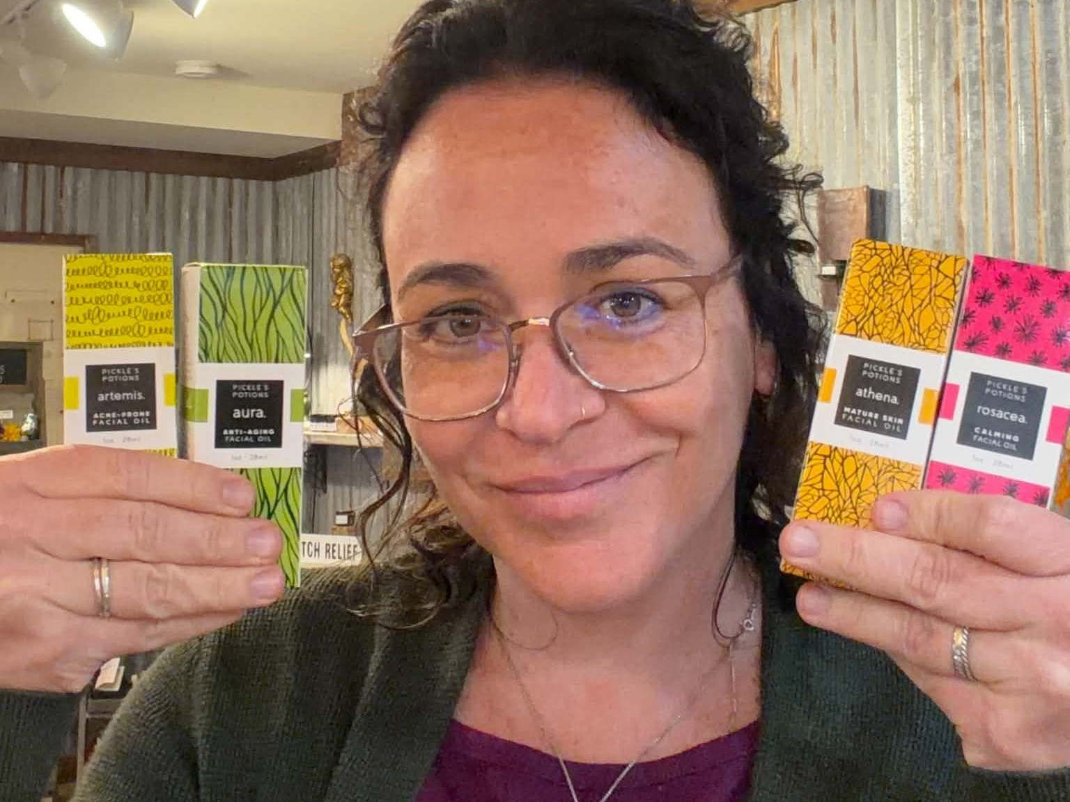 Pickle from Pickles Potions holding her four facial oil variations for acne-prone skin, aging mature skin, antiaging formula, and the rosacea blend.