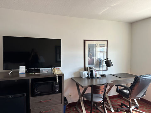 Ramada Sherwood Park guest room featuring a workspace with desk and comfortable chair alongside a large flat-screen TV