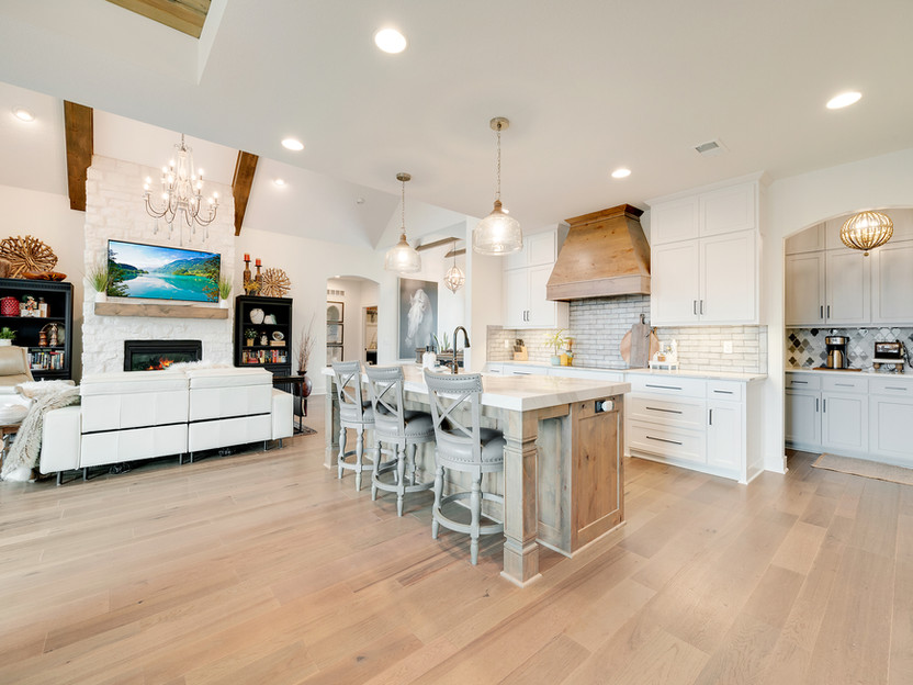 Spacious kitchen with island and seating, white cabinets and wooden floors.