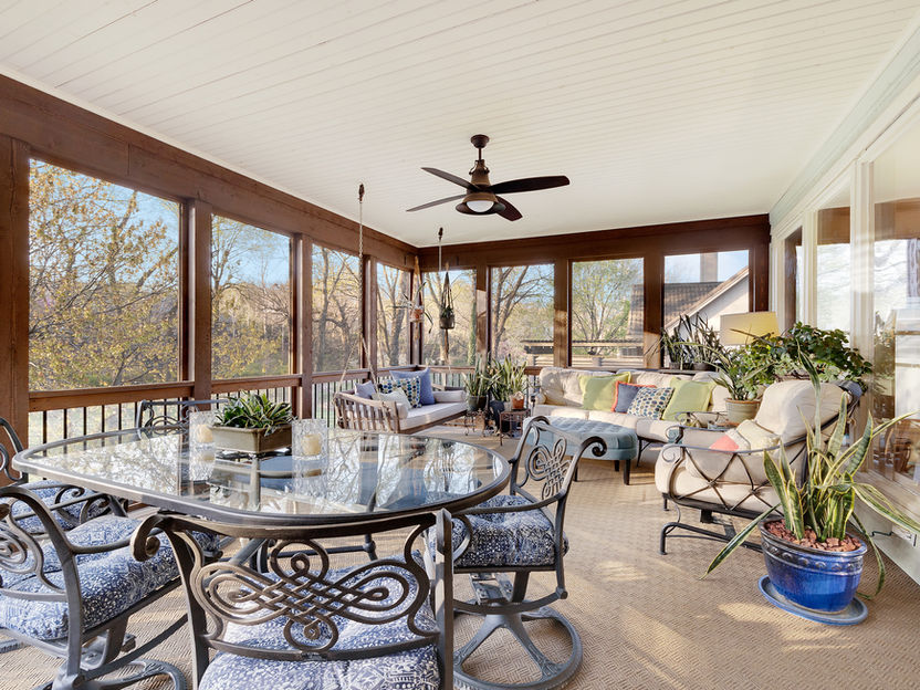 Patio with table and chairs, trees visible through open windows. Neutral décor
