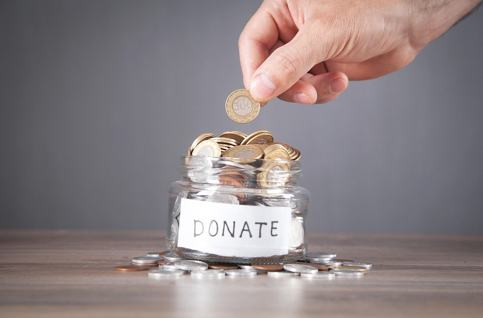 A hand placing a coin into a donation jar filled with money, symbolizing charitable giving.