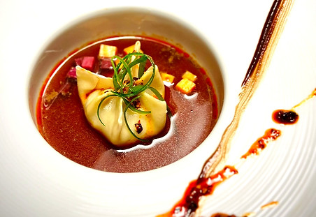 duck soup dumpling in a black garlic shitake duck dashi pickled ube and golden yam chile crunch.