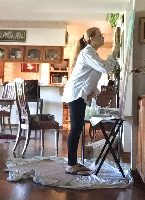 Madhavi Devi paints in a standing position in a bright studio.