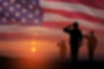 Silhouettes of soldiers saluting on background of sunset or sunrise and USA flag. Greeting