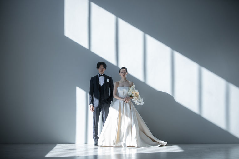 A male and female model wearing a white dress and tuxedo posing together